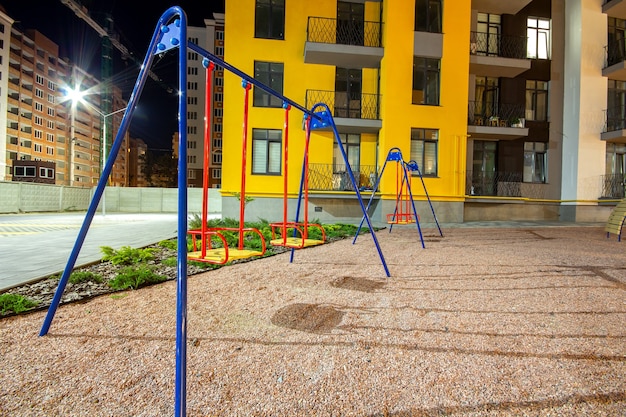 Parco giochi per bambini di notte nel cortile del quartiere residenziale tra condomini.