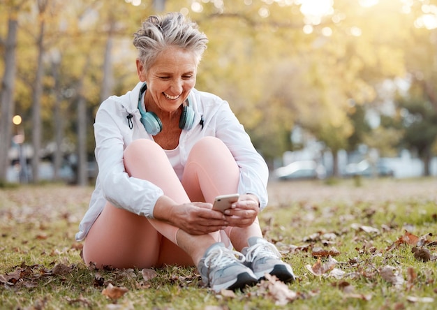 Parco per smartphone e donna anziana con app per la salute mentale per il benessere della natura e post sul blog del sito Web per una vita di pensionamento sana Donna anziana o anziana che utilizza il telefono o digita sul cellulare e si rilassa sull'erba