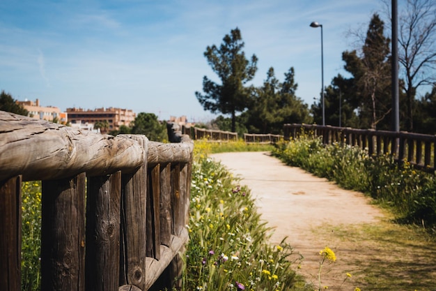 Parco urbano con strada sterrata e recinzioni in legno con edifici sullo sfondo Copia spazio