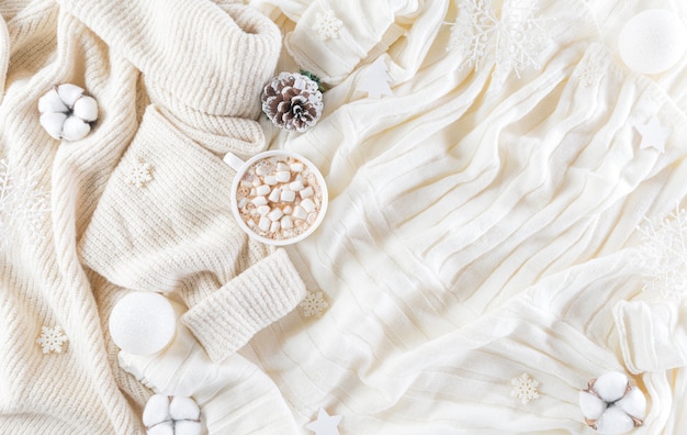 Parete accogliente invernale con tazza di caffè, maglione caldo, confezione regalo, fiore di cotone e palla di Natale sulla parete del tappeto di lana, vista dall'alto con spazio di copia