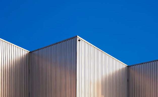 Parete in acciaio ondulato di edifici industriali su sfondo blu cielo chiaro