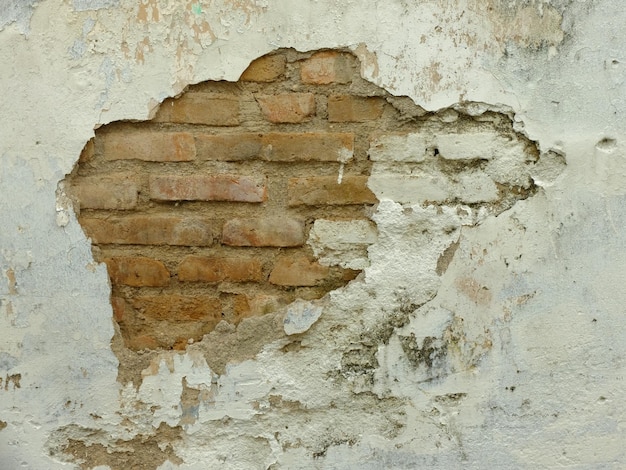 pareti di cemento bianco che si staccano dalla superficie. mattoni tra i muri rotti. casa abbandonata.