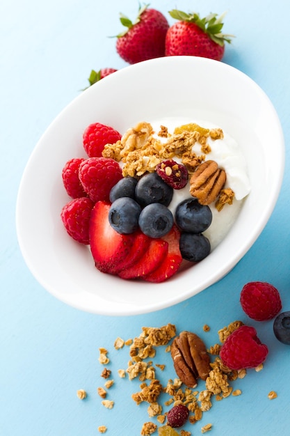 Parfait con frutta fresca e muesli in una ciotola bianca.