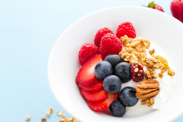 Parfait con frutta fresca e muesli in una ciotola bianca.