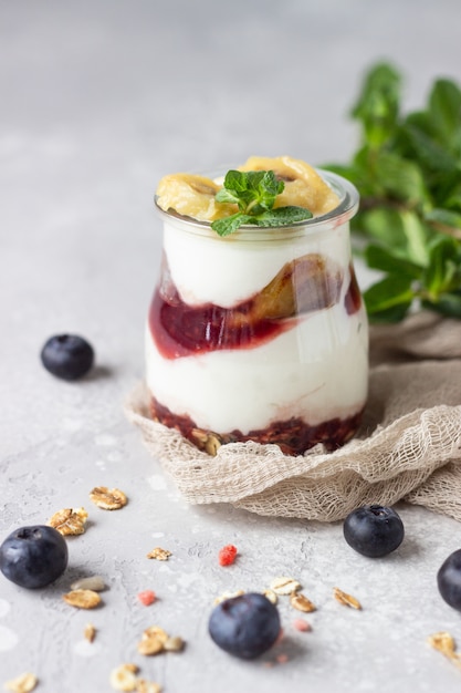 Parfait di yogurt greco muesli, mirtilli e banana in barattoli di vetro