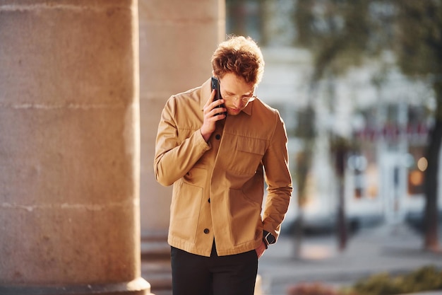 Parlando al telefono Elegante giovane uomo in abiti formali di classe all'aperto in città