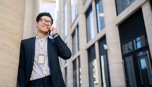 Parlando Uomo d'affari manager allegro utilizzando il telefono in un vestito con gli occhiali andando a lavorare