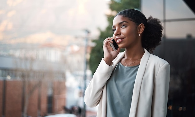 Parlare al telefono, comunicare e fare rete con una giovane donna d'affari sicura e ambiziosa su un balcone Designer professionista e creativo su una chiamata per discutere e pianificare il lavoro