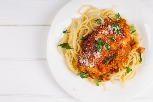 Parmigiana di pollo su un piatto bianco con spaghetti.