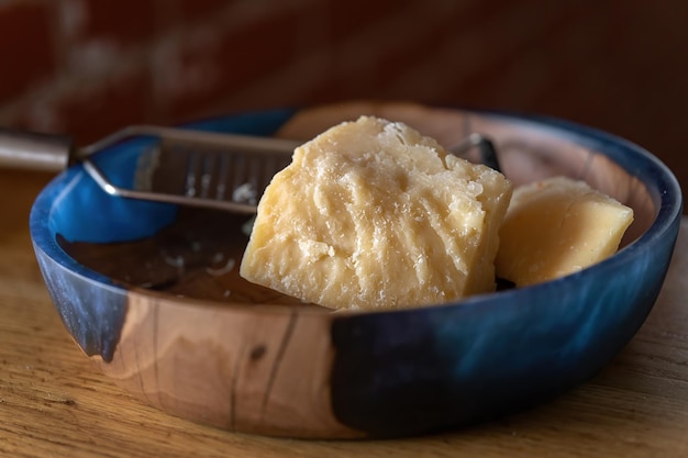 Parmigiano con una grattugia Profondità di campo Bella piastra in legno Macro