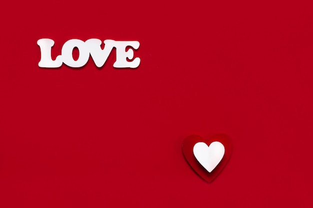Parola amore da lettere bianche e simbolo a forma di cuore rosso bianco su sfondo rosso Primo piano vista dall'alto Concetto di giorno di San Valentino