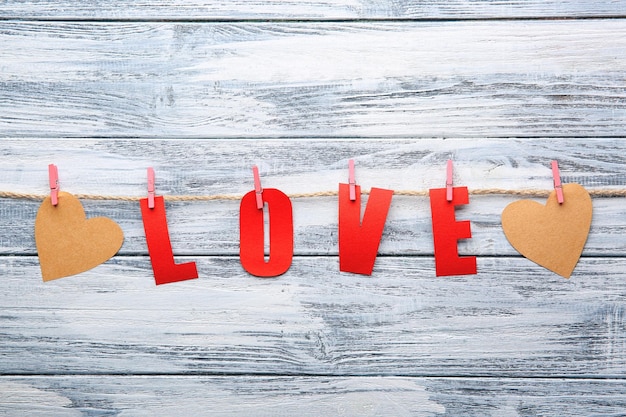 Parola AMORE fatta di lettere di carta con cuori su fondo di legno