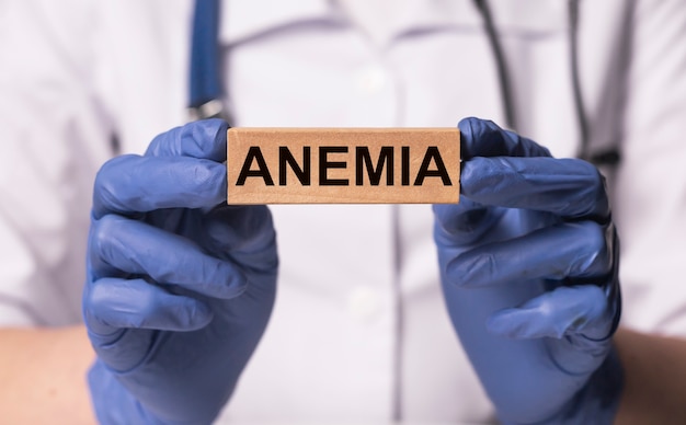 Parola di anemia sul blocco di legno in mano del medico