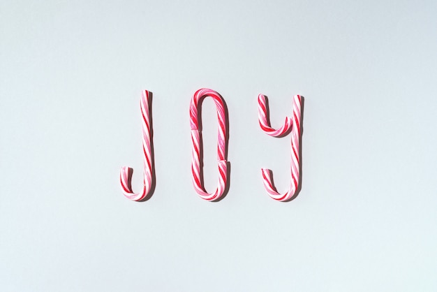 Parola di gioia scritta con i bastoncini di zucchero di Natale su fondo grigio