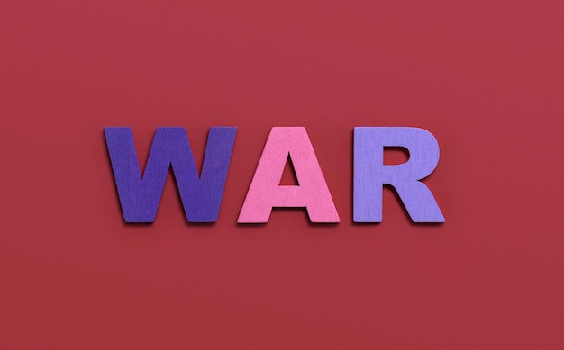 Parola di GUERRA scritta in lettere dell'alfabeto in legno colorato su sfondo rosso Il concetto di una guerra terribile che distrugge il paese Vista dall'alto Spazio di copia