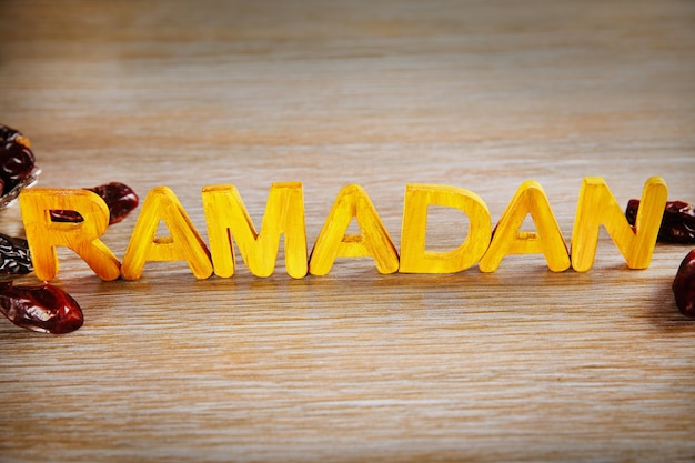 Parola di Ramadan con lettere di legno e datteri secchi sul tavolo