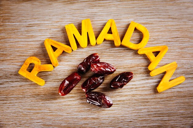 Parola di Ramadan con lettere di legno e datteri secchi sul tavolo