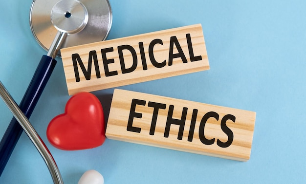 Parola etica scritta su blocchi di legno e stetoscopio su sfondo blu Concepto sanitario per la clinica ospedaliera e concetto medico