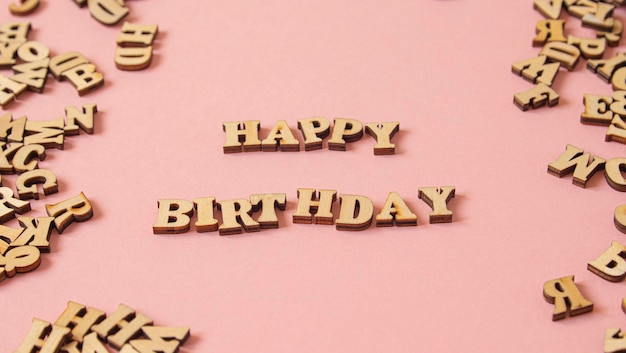 Parola quotHappy Birthdayquot scritta in inglese con lettere di legno su sfondo rosa