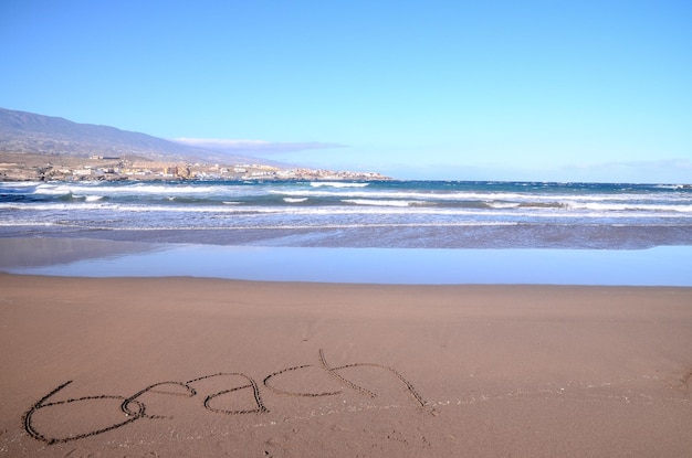 Parola scritta sulla sabbia di una spiaggia tropicale