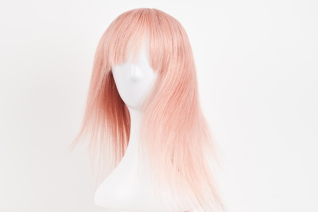Parrucca bionda rosa naturale su testa di manichino bianca capelli lunghi tagliati sul portatore di parrucca di plastica isolato su sfondo bianco