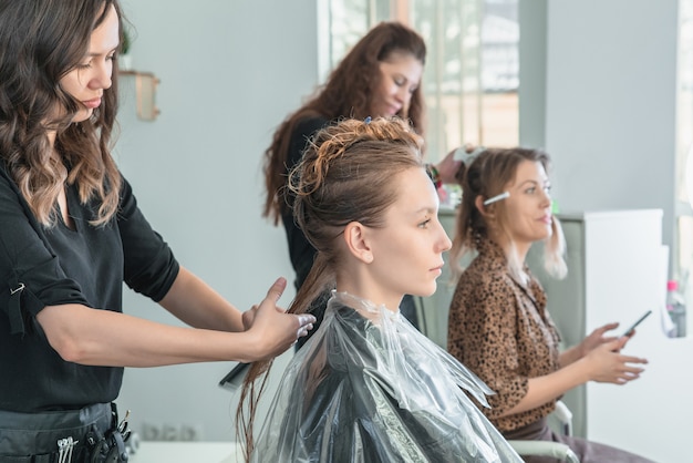 Parrucchiere che colora i capelli della giovane donna facendo uso di stagnola