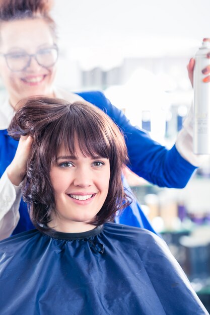 Parrucchiere che disegna i capelli della donna in negozio