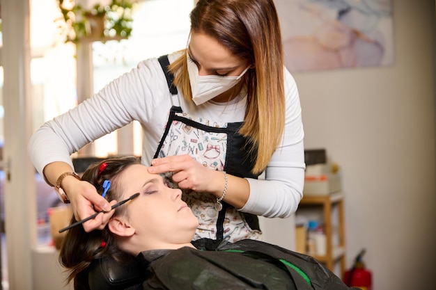 parrucchiere che fa il trucco e lo styling di una giovane cliente femminile in un salone di bellezza