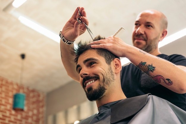 Parrucchiere che fa taglio di capelli maschile a un uomo attraente nel salone di bellezza