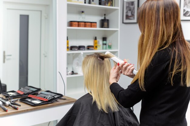 parrucchiere che fa uno stile elegante alla donna in salone