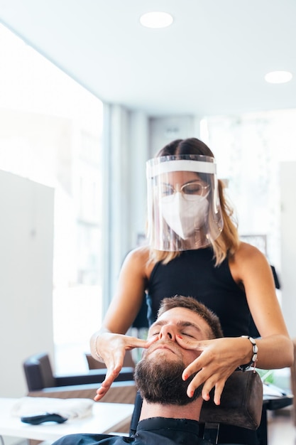 Parrucchiere che massaggia il viso del cliente in un parrucchiere