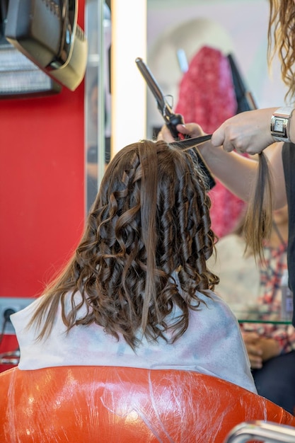 Parrucchiere che ondeggia i capelli lunghi di una ragazza da uno stilista professionista