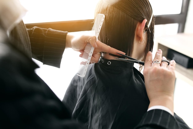 Parrucchiere che taglia capelli castani con le forbici