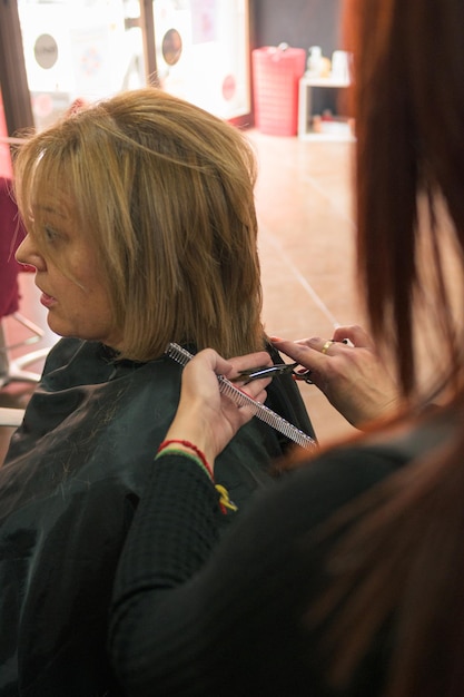 Parrucchiere che taglia e disegna i capelli di una donna