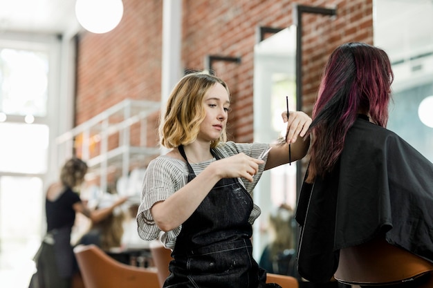 Parrucchiere che taglia i capelli della cliente in un salone di bellezza