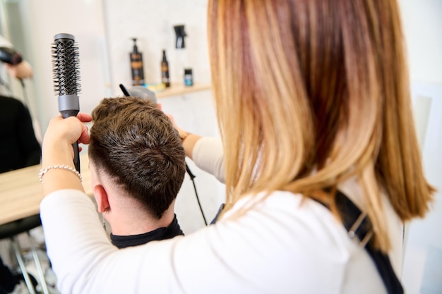 Parrucchiere che taglia i capelli e acconcia un cliente nel negozio di barbiere