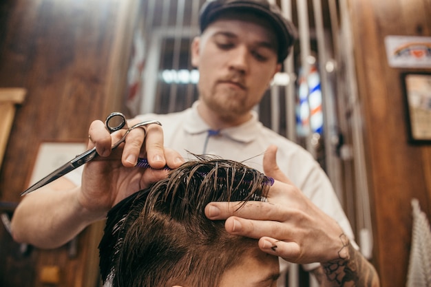 Parrucchiere di tagli di capelli dell'adolescente nel negozio di barbiere