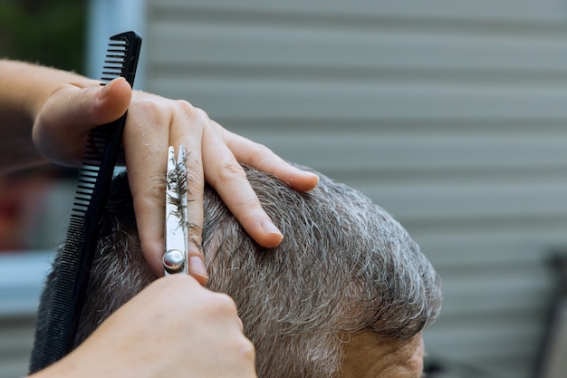 Parrucchiere donna che taglia i capelli di un uomo in un parrucchiere in casa