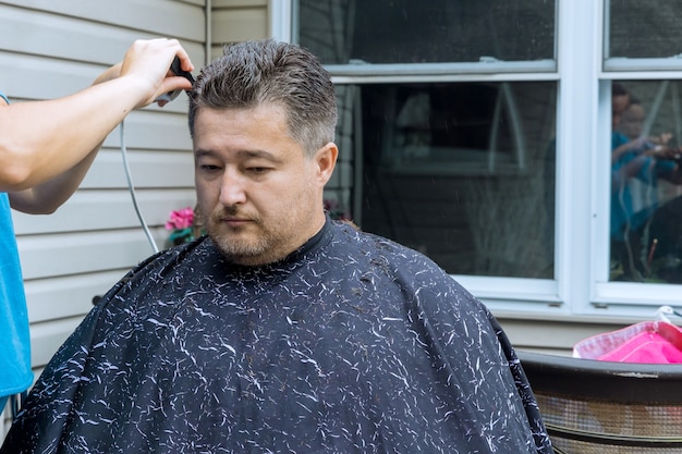 Parrucchiere donna che taglia i capelli di un uomo in un parrucchiere in casa