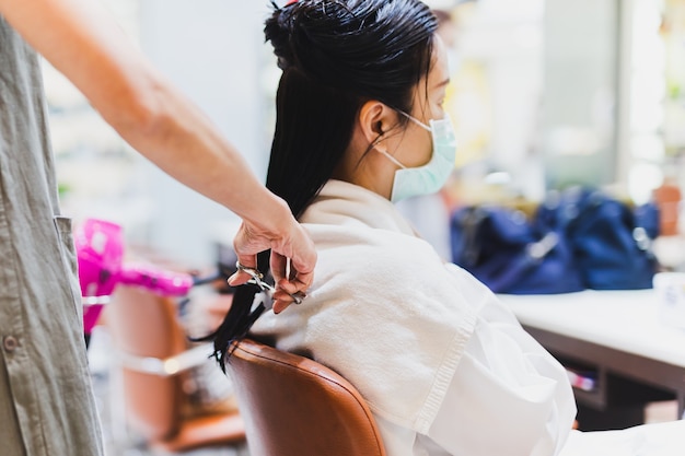 Parrucchiere donna con le forbici che inizia a tagliare i capelli del cliente