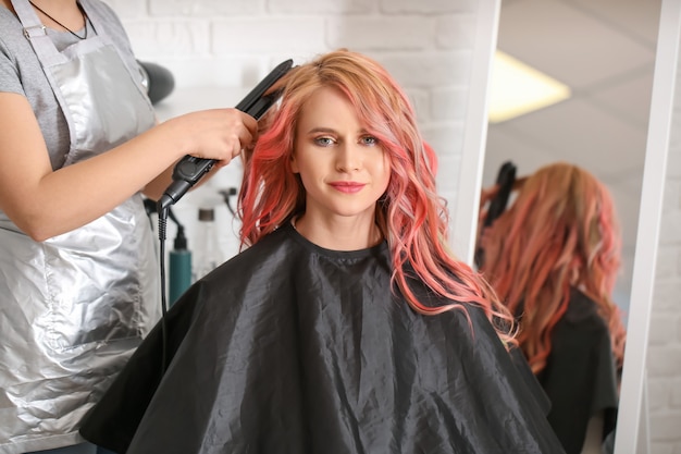 Parrucchiere femminile che fa i capelli di bella giovane donna in salon