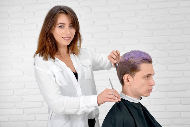 Parrucchiere femminile che fa taglio di capelli per il giovane cliente con i capelli tonica.