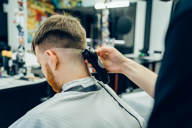 Parrucchiere maschio che taglia i capelli di un cliente