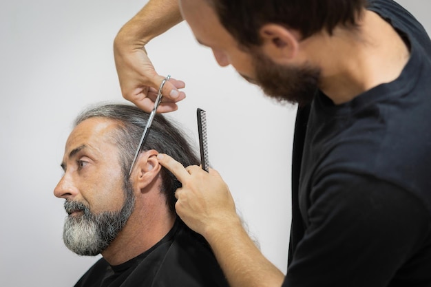 Parrucchiere maschio che taglia i capelli per il cliente maschio