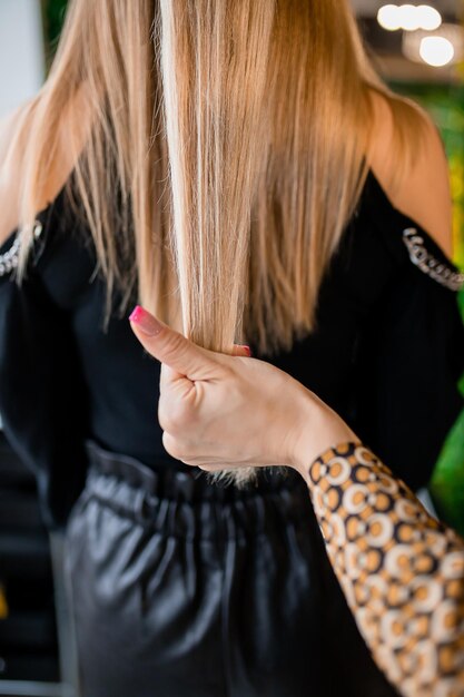 Parrucchiere professionista che prepara i capelli biondi per le estensioni in un salone di bellezza