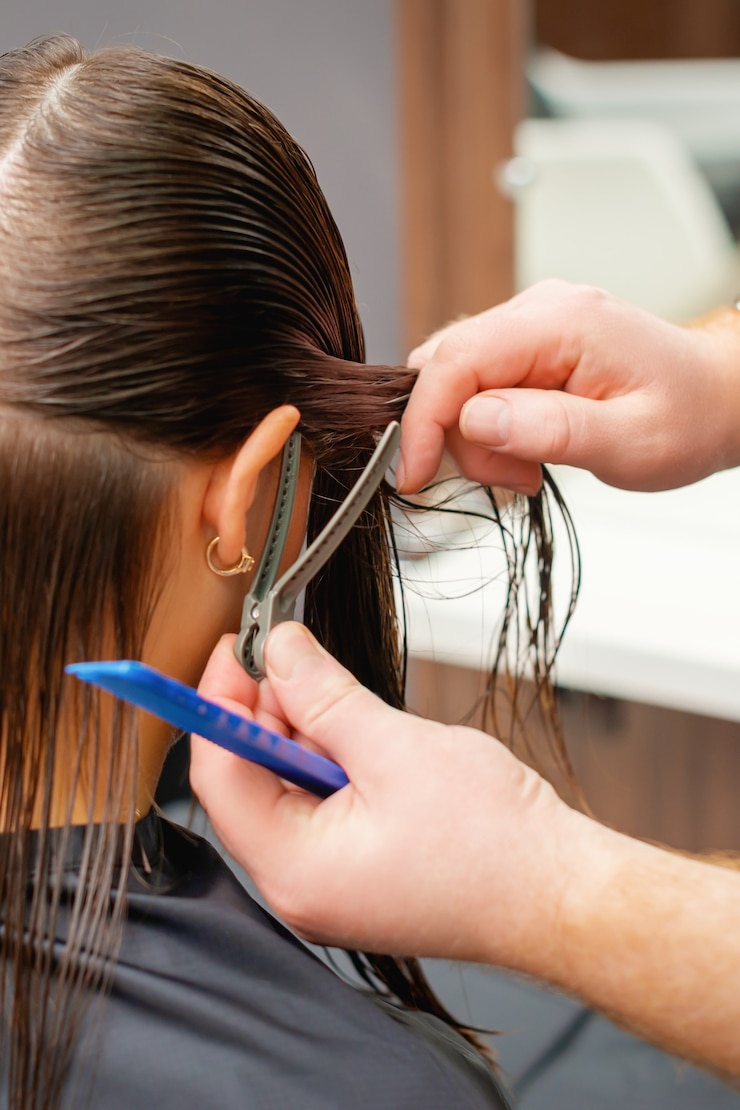 Foto parrucchiere professionista che taglia i capelli di una giovane donna