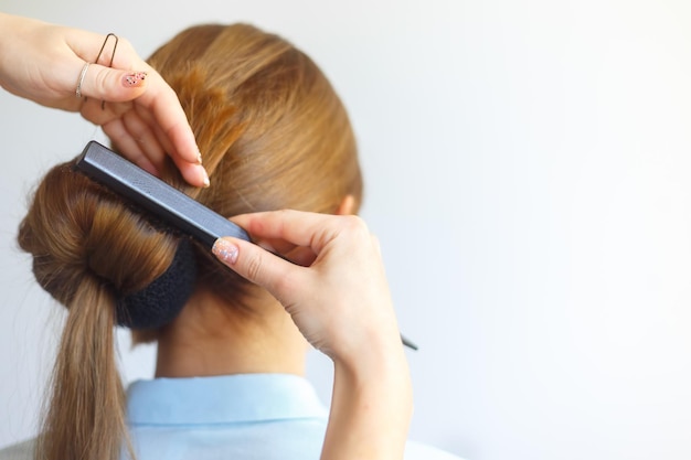 Parrucchiere professionista femminile che fa acconciatura a una giovane donna allegra con i capelli lunghi