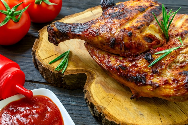 Parte al forno di gustoso pollo, con crosta marrone dorato, cotta sul barbecue sul tavolo di legno scuro.