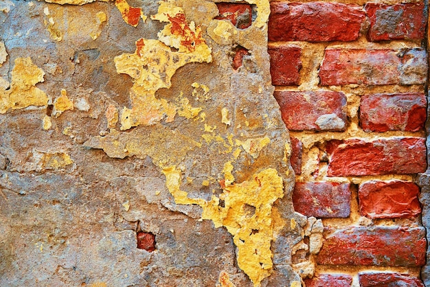 Parte astratta di un vecchio muro di mattoni con intonaco distrutto per uno sfondo in stile vintage e loft