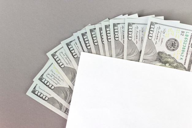 Parte del foglio di carta bianco vuoto con banconote americane da 100 dollari fatte di carta poste su sfondo grigio